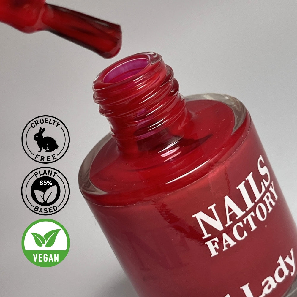 Grüner, pflanzenbasierter Nagellack Red Lady von claire beauty, Farbswatch auf Nagelprobe, umgeben von grünen Blättern